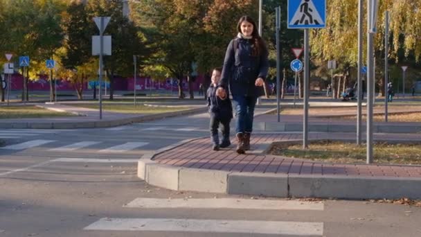 Máma a dítě přejít silnici na přechodu zebry. — Stock video