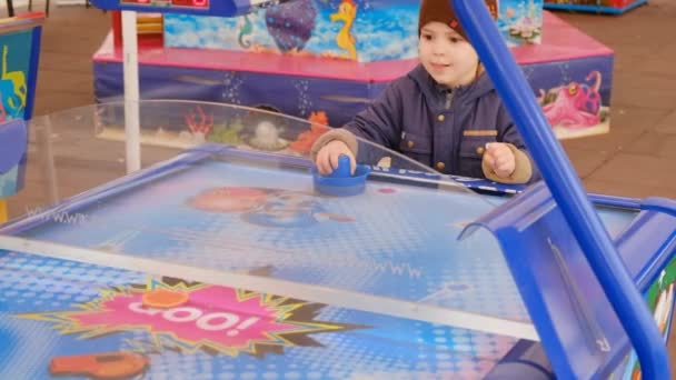 The boy plays air hockey, licks and delightfully beats the puck, scores a goal — Stock Video