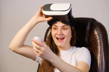 Sanal gerçeklik gözlüklü bir kadın uzaktan kumandaya bakar..