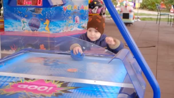 The child plays air hockey outdoors and talks. — Stock Video