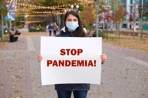 Una mujer con una máscara médica sostiene un cartel que dice Stop Pandemia — Foto de Stock