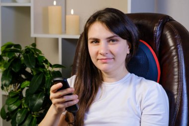 Kadın kontrol panelini kullanarak boyun altındaki masaj yastığını kontrol ediyor..