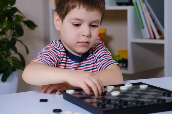 Un niño preescolar de 4 años juega un juego de mesa de damas —  Fotos de Stock