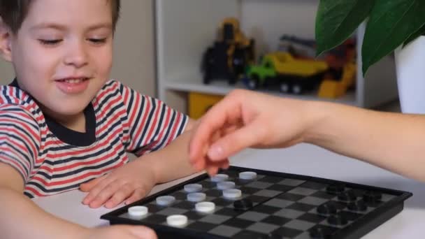 Maman apprend à son fils à jouer aux dames. Jeux de société pour les enfants d'âge préscolaire, repos en quarantaine. — Video