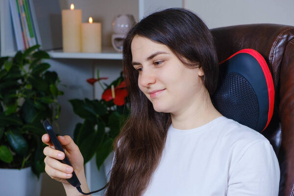 Женщина управляет массажной подушкой под шеей с помощью панели управления