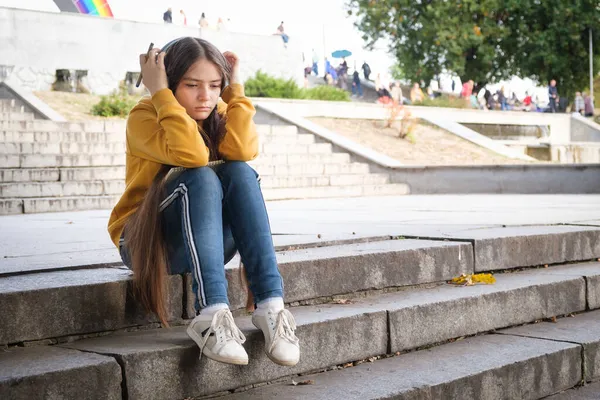 Una adolescente triste se sienta en las escaleras y se cubre la cabeza con las manos — Foto de Stock