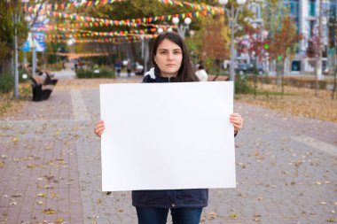 Ciddi yüzlü bir kadın bir yazı için boş bir sayfa tutuyor..