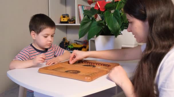 Mutter bringt ihrem Sohn bei, lange Backgammon zu spielen. Brettspiele für Vorschulkinder und Kinder. — Stockvideo