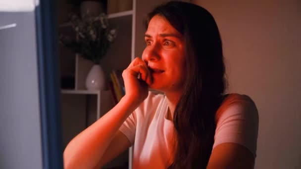 Женщина смотрит фильм ужасов в темноте, грызет ногти от опыта — стоковое видео