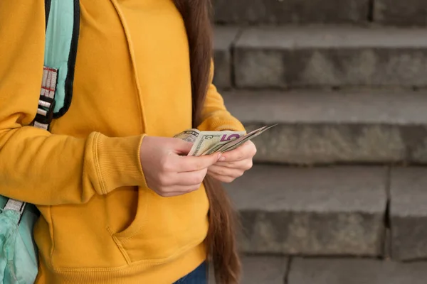 Дівчинка-підліток рахує доларові купюри на тлі сходів — стокове фото