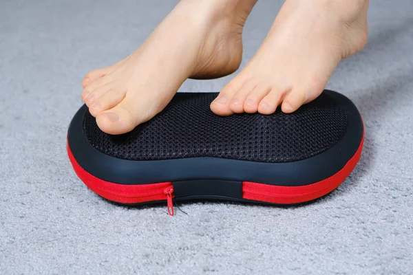 Womens feet on a massage pillow, relieving leg fatigue after a days work. — Stock Photo, Image