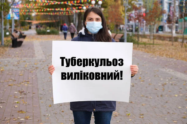 Maskovaná žena je držitelem plakátu s textem ukrajinsky, přeloženým z ukrajinštiny - Tuberkulóza je léčitelná — Stock fotografie