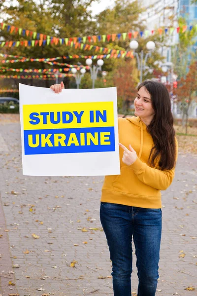 Женщина улыбается и держит плакат с текстом Study in Ukraine — стоковое фото