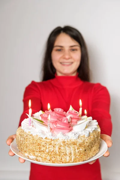 赤い服のブルネットの女性はキャンドル付きの大きな白いケーキを保持し 願いを作ります — ストック写真