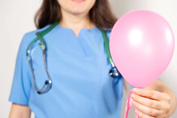 身着蓝色制服的医生或护士拿着一个粉色气球 上面写着医生的日子 — 图库照片