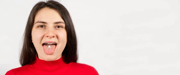 Een vrouw neemt een pil, een witte ronde pil op de tong in een persoon mond — Stockfoto