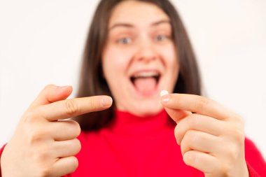 Bir kadın elinde bir hap tutuyor ve onu işaret ediyor, beslenme takviyeleri ve tıpta tedavi.