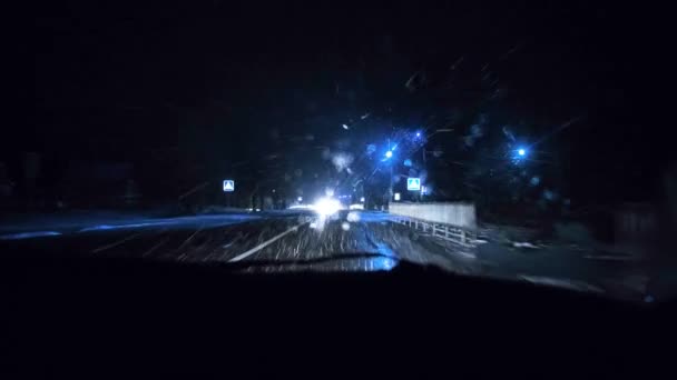První sníh v zimě v noci, pohled z auta při jízdě, světlo reflektorů. — Stock video
