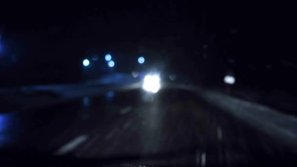 夜間の冬の最初の雪、運転中の車からの眺め、車のヘッドライトの光. — ストック動画
