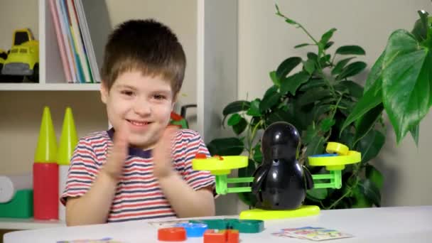 Un niño preescolar aprende números, pesa números en una balanza de pingüinos — Vídeos de Stock