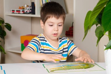 Anaokulu öğrencisi bulmacalardan bir timsah resmi yapıyor.