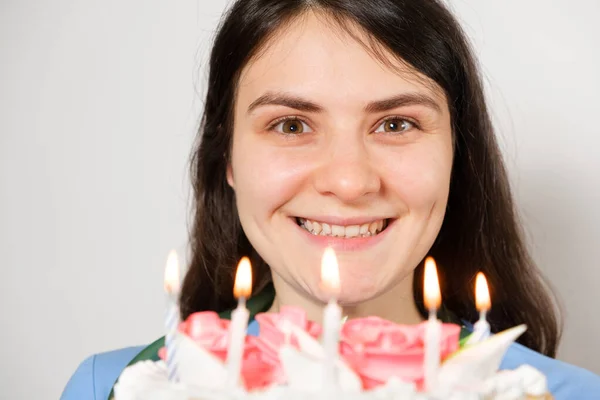 Una doctora con uniforme azul sostiene un pastel de cumpleaños con velas y sonrisas. —  Fotos de Stock