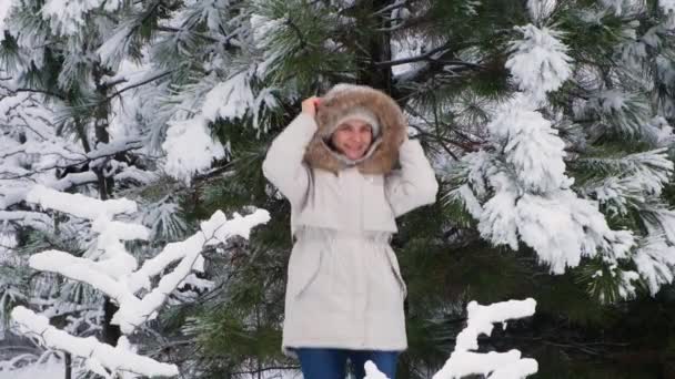 한 여자가 뛰면서 겨울 눈덮인 숲에서 재미있게 놀고 있는 모습, 눈송이들이 천천히 나는 모습 — 비디오