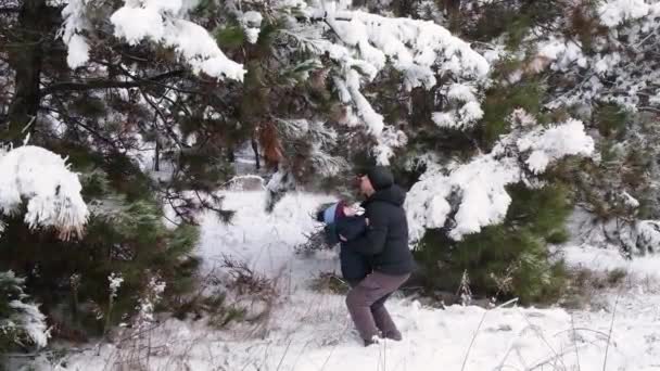 A father tosses his son up, spending time in the winter snowy forest — 图库视频影像