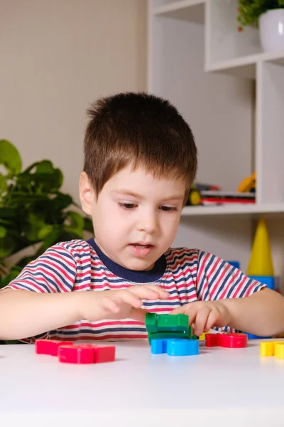 Um menino de 4 anos brinca com números multicoloridos, constrói uma torre — Fotografia de Stock