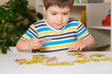 Anaokulu öğrencisi bulmaca oynar, resim yapar.