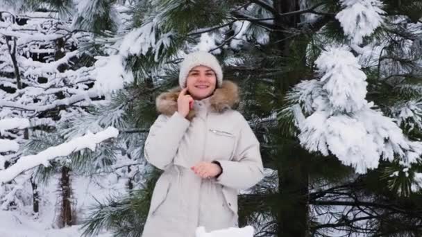 Piękna kobieta bawi się w zimowym lesie sosnowym, patrząc w kamerę — Wideo stockowe