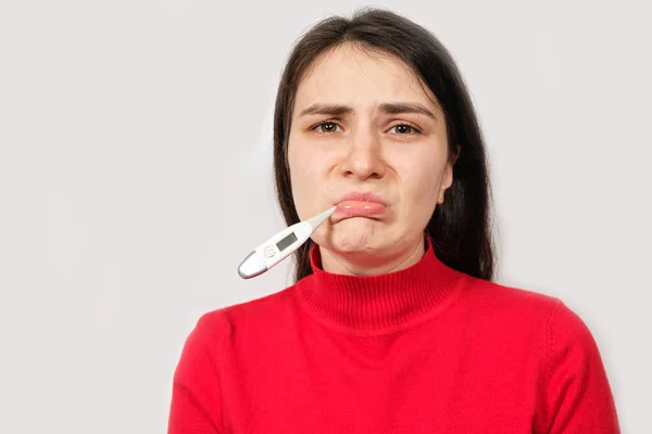 Uma triste mulher doente com um termômetro na boca olha para a câmera, copiando espaço para texto. — Fotografia de Stock