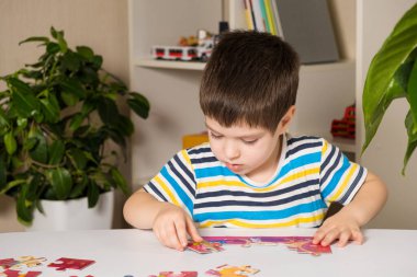 Anaokulu öğrencisi bulmaca oynar, resim yapar.