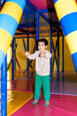 4 yaşında bir anaokulu çocuğu, oyun odasında boks yapmak için kum torbasıyla, çocuklar için de eğlence merkezi ile oynuyor..