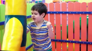 4 yaşında bir anaokulu çocuğu oyun odasında boks yapmak için kum torbasıyla oynuyor. Çocuklar için eğlence merkezi.