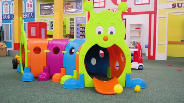 Een jongen speelt in een doolhof in de vorm van een rups in een kinderspeelkamer — Stockvideo