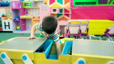 Anaokulundan bir çocuk, çocuklar için bir oyun odasında inşaat seti oynuyor.