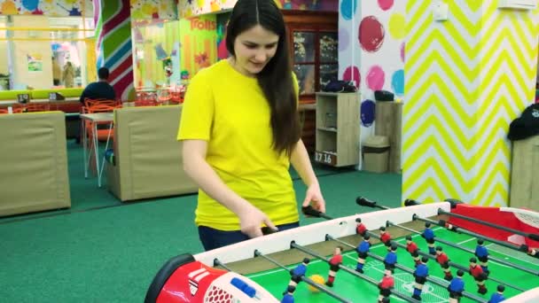 Uma mulher em uma camiseta amarela joga futebol de mesa na sala de jogos — Vídeo de Stock