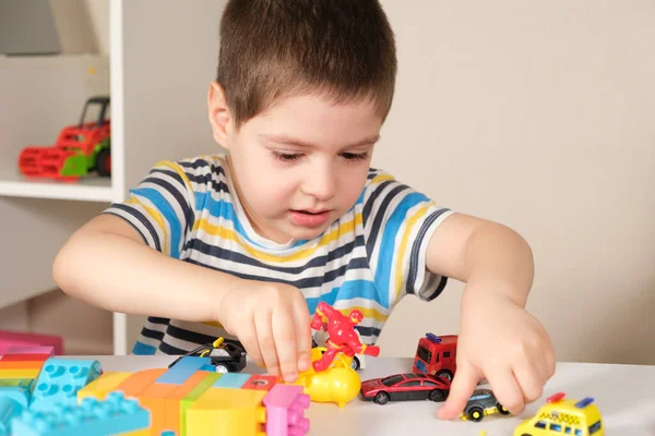 Un beau garçon de 4 ans joue avec des voitures et un ensemble de construction, des jeux d'enfants d'âge préscolaire, le développement de l'imagination. — Photo