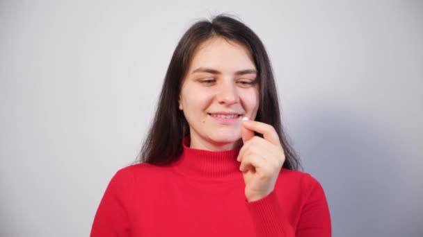 A beautiful woman takes a pill, shows it on her tongue and smiles. — Stock Video