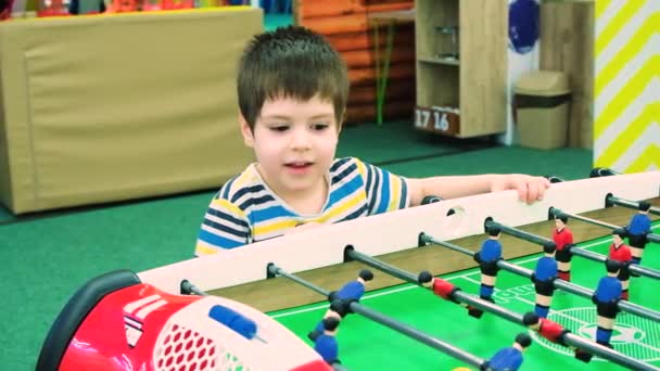 Menino pré-escolar bonito jogando futebol de mesa, se divertindo e pulando, tiro em câmera lenta. — Vídeo de Stock