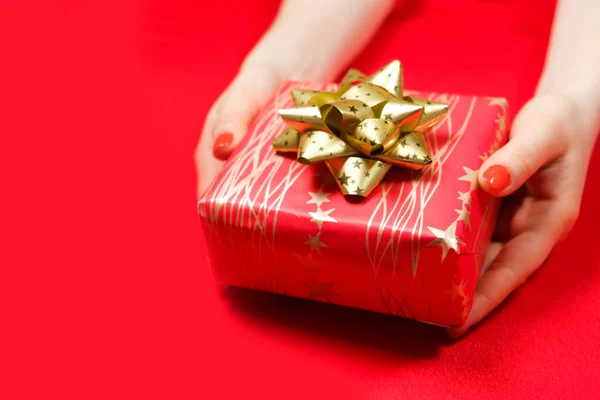 Piros gyönyörű ajándék sárga arany íj a kezében egy nő piros körömlakk, másolás helyet a szöveg — Stock Fotó