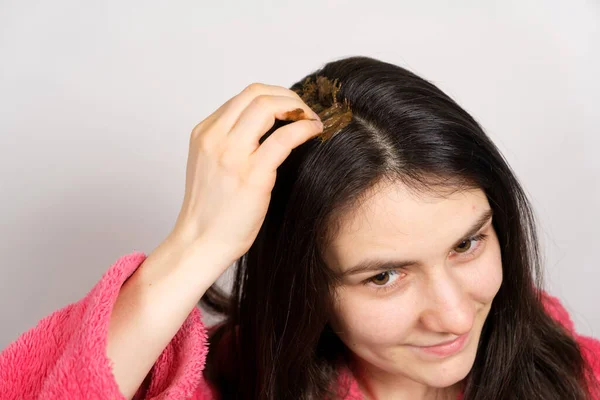 Una mujer morena aplica una mezcla ayurvédica natural de hierbas a su cabello, mascarilla para el cuero cabelludo y exfoliante, cuidado del cabello en casa. — Foto de Stock