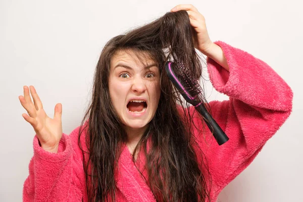 Una mujer con el pelo enredado largo húmedo trata de peinar — Foto de Stock