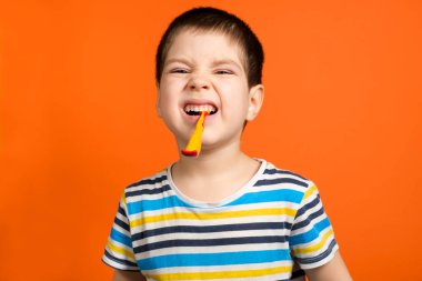 3-5 yaşlarında bir çocuk dişlerini turuncu bir arka planda fırçalıyor, yazı için yeri kopyalıyor. Çocuklarda süt dişlerine dikkat et.