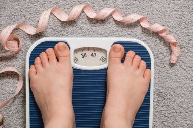 Kadın ayakları yer ölçeğinde, üst manzara. Bir ölçekte 30-40 kilo, iştahsızlık ve yeme bozuklukları fikri