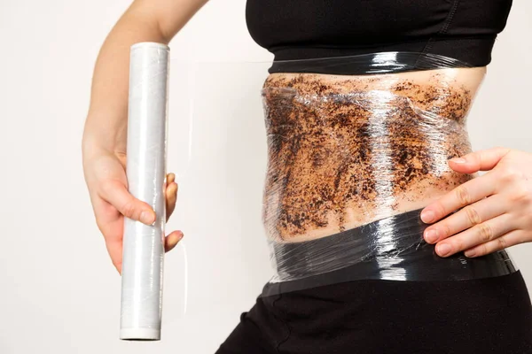 Une femme fait un enveloppement de ventre avec un gommage anti-cellulite café. Le concept de perte de poids et de soins de la peau — Photo