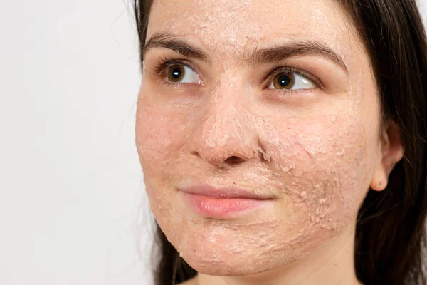 Seorang wanita muda yang cantik mengoleskan scrub atau masker ke wajahnya, perawatan kulit wajah, pembersihan kulit — Stok Foto