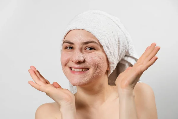 Egy fiatal, mosolygós nő természetes maszkkal vagy ubtan arccal és fehér törölközővel a fején, egy hely, ahol SMS-ezhet, lemásolhatja a helyet. — Stock Fotó