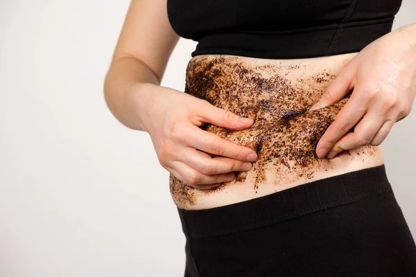 The woman applied a coffee scrub to her abdomen and showed the problem areas, belly fat. The concept of body care and weight loss. — Stock Photo, Image